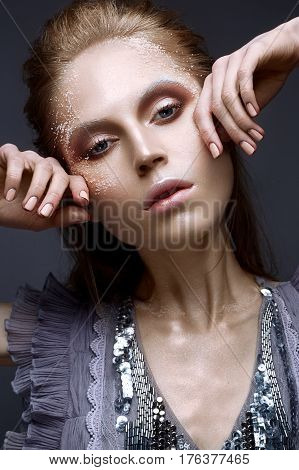 Young girl with creative makeup and textures on her face. Beautiful model in a lilac dress with sparkles. Photo is taken in the studio. Beauty of the face.