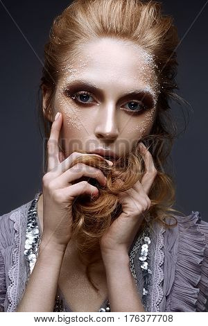 Young girl with creative makeup and textures on her face. Beautiful model in a lilac dress with sparkles. Photo is taken in the studio. Beauty of the face.