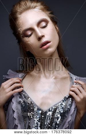 Young girl with creative makeup and textures on her face. Beautiful model in a lilac dress with sparkles. Photo is taken in the studio. Beauty of the face.