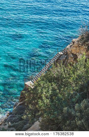 Stairs over rock leading down to lagoon and turquoise sea waters at South Mediterranean coast of Turkey near Koru beach in Gazipasa town