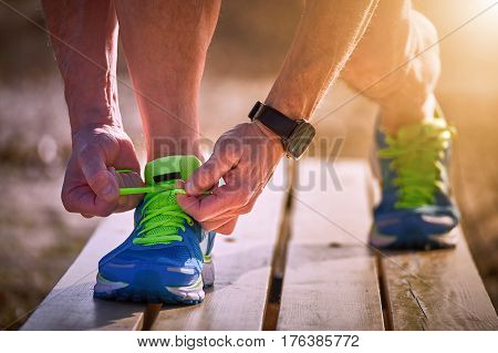 Athlete during training tying shoelaces on sneakers summer.