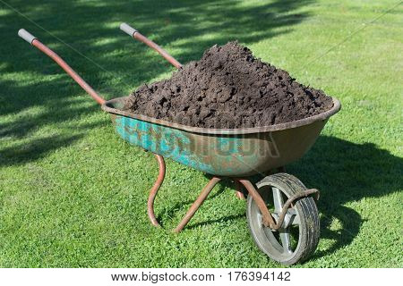 Garden-wheelbarrow filled with soil on a farm.