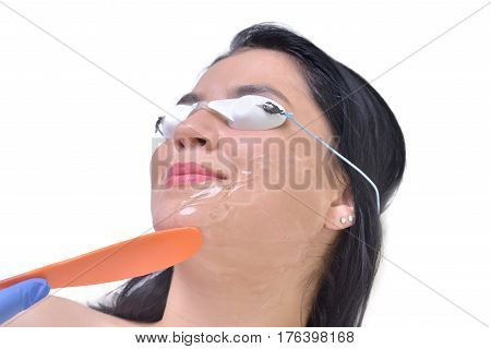 Beautiful young woman lying on a table with protect glasses on eyes getting a laser skin treatment