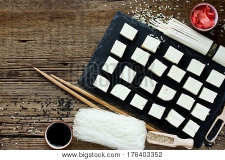 Set of traditional japanese food on wooden background. Asian food background tofu soy sauce sesame paste udon rice noodles pickled ginger. Empty place for text
