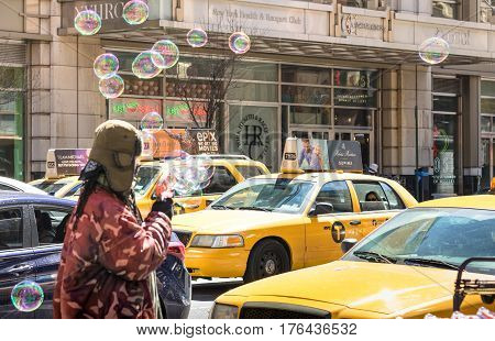 NEW YORK CITY - 30 MARCH 2015: unidentified vendor blowing soap bubbles on the streets of Manhattan with yellow taxi cabs - Everyday life on the cultural and financial capital of the world
