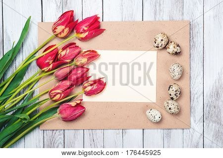 Easter eggsbeautiful red tulips blank note on the wooden background.