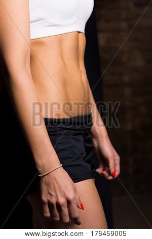 Slender female belly against a brick wall.