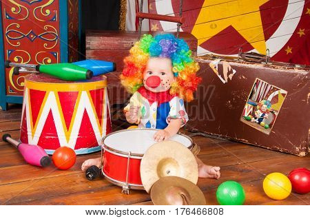 Little baby clown with red nose multi-colored wig in with balls.