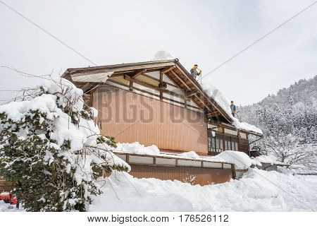 Shirakawa, Japan - 14 FEB 2017: Worker cleaning roof house from snow at Shirakawa-go village, Japan.Winter in Shirakawa-go Japan