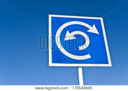 Roundabout traffic sign over a blue sky