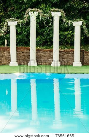 Decorated with flower garland columns behind turquoise pool