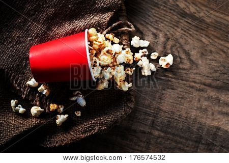 Fresh Popcorn in a red cardboard box on the wooden table Cinema concept