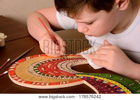 The child paints the colors of the wood