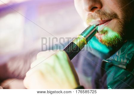 Young Vaper Man With Beard Vaping Mechanical Mod. Guy Smokes An Electronic Cigarette By Blowing A Sm