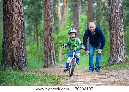 Happy cute blond kid boy having fun his first bike on sunny summer day outdoors. Happy child making sports. Active leisure for children.Kid boy wear safety helmet. boy is smiling and cicling.
