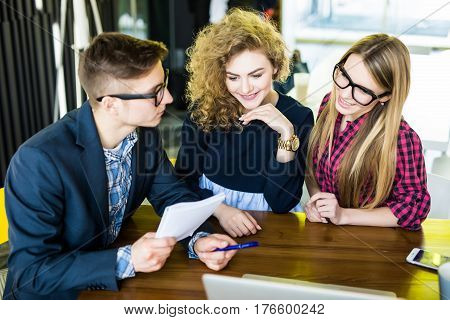 Group Of Friends Working On Their Small Business Modern Office. Man Show On His Notice On Notebook