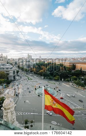 View of Square of Cibeles from Town Hall of Madrid at sunset. Spanish glag on foreground