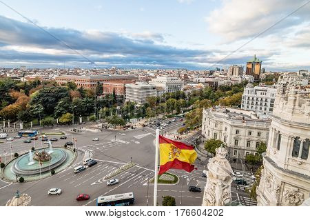 View of Square of Cibeles from Town Hall of Madrid at sunset. Spanish glag on foreground