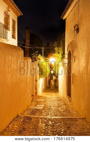 Cobblestone narrow street in historic Albacyn district of Granada at night
