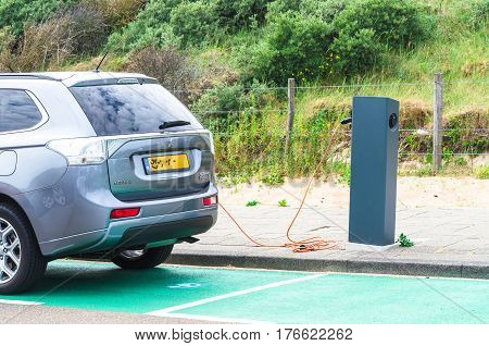 DEN HAAG SCHEVENINGEN THE NETHERLANDS - JUNE 17 2015: Electric car at a charging station on the beach parking in Scheveningen Holland. Seperate parking with charging station for electric vehicles. Vehicles can be connected by cable to the station for rech