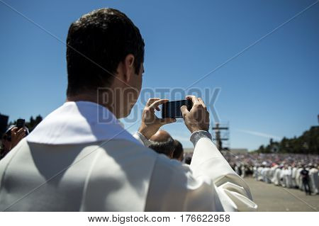 Fatima Portugal - May 13 2014: Priest taking a photograph with his mobile phone at the Sanctuary of Fatima during the celebrations of the apparition of the Virgin Mary in Fatima Portugal.