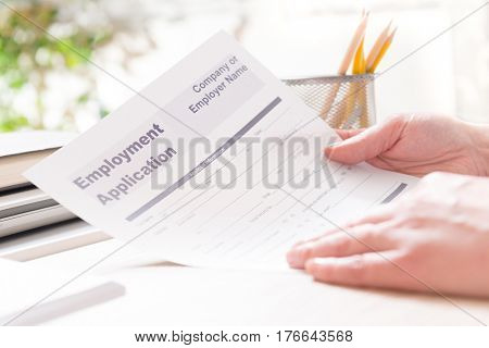 Blank employment application form in hands on a desk