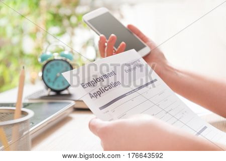 Blank employment application form in hands on a desk