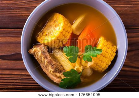 Puchero Soup With Corn And Parsley On Wooden Table