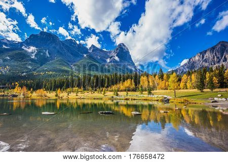 Shallow lakes surrounded by forests and mountains. Shining day in Canmore, Canadian Rockies. Concept of hiking