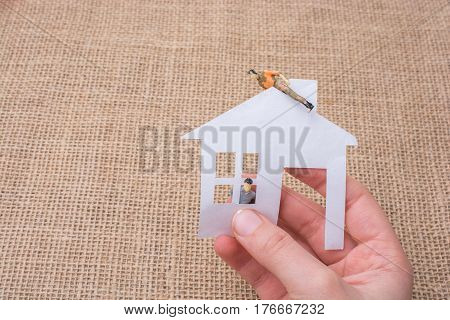 Paper house and a man figurine on a linen canvas background