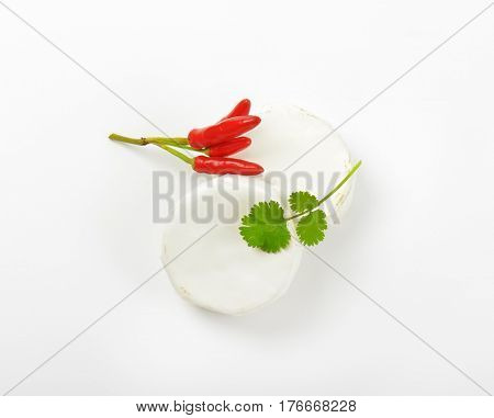 Wheels of soft white cheese and red chili peppers