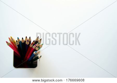 A lot of colored pencils inside a tin can on the white background.