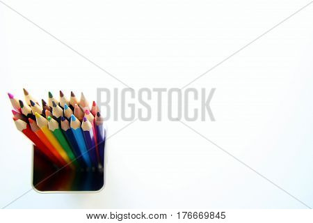 A lot of colored pencils inside a tin can on the white background.