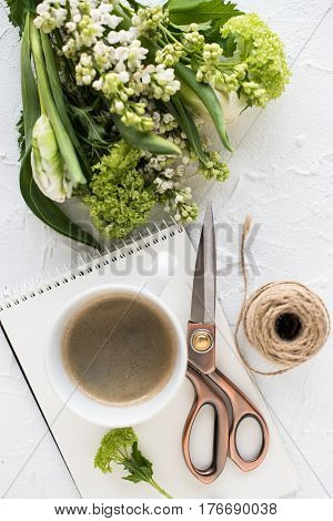 Feminine flatlay with spring flowers and ccoffee on white textured tabletop
