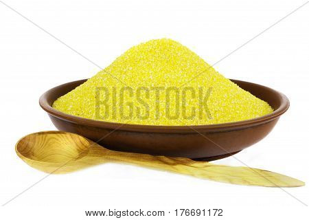 Corn grits in clay bowl isolated on white with wooden spoon