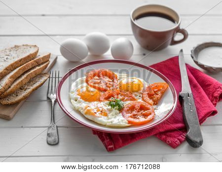 Eggs fried overeasy served on white plate, tableware and red napkin, coffee on side