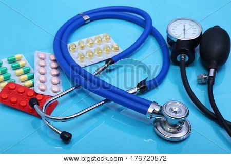 Stethoscope, red heart, asorted pils and medical equipmenton on blue background.
