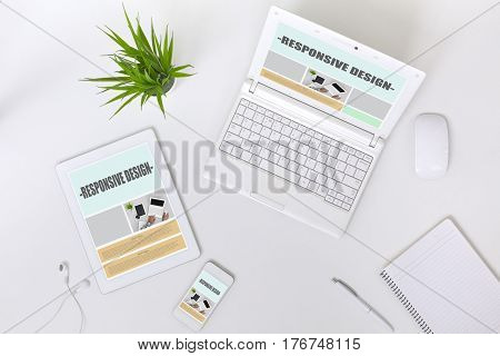 Working Place of web Designer on white Table with responsive Site Theme on Laptop Tablet and Telephone Screens and blank Page of Paper Notepad Top View flat Lay.