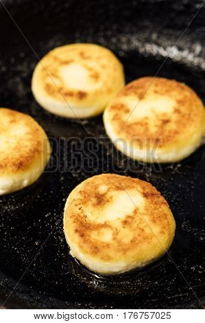 Cheesecakes. Beautiful pancakes made of cheese in a black frying pan. Cheesecakes. Pancakes curd. Pancakes fritters, a traditional dish of Russia and Ukraine.