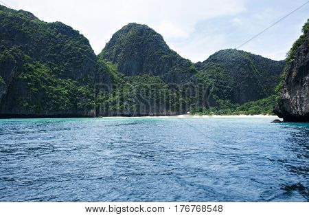 Deserted tropical white sand beach bay at midday surrounded by green mountains and turquoise blue ocean water used for holidays and relaxation and nobody around in Krabi Thailand