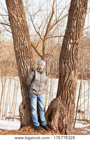 The man in spring clothes costs at a tree in the spring