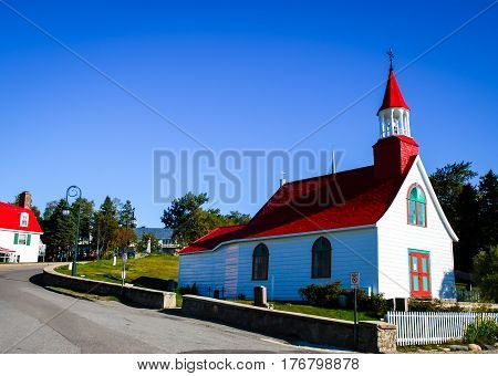 small red and white church in tadoussac canada on a blue sky background