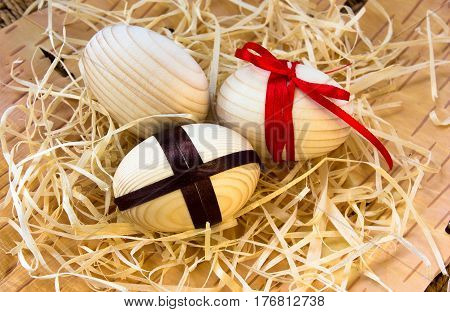 Easter eggs with ribbon and red flowers. Background birch bark and straw