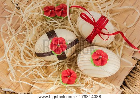 Easter eggs with ribbon and red flowers. Background birch bark and straw