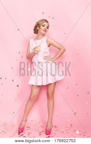 Pretty young woman with a sham glass posing on the pink background. Vertical studio shot.
