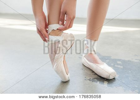 Close up of ballerina tighten the pointes on a grey background