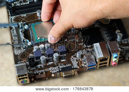 Computer motherboard and hand with procesor close up