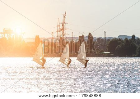 Windsurfers are trained on a large lake. Evening shot.