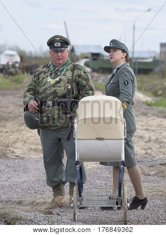 SAINT PETERSBURG, RUSSIA - MAY 05, 2015: The man in the form of the field gendarmerie and the girl in the uniform of a German with a pram. Reconstruction of the episode of the great Patriotic war