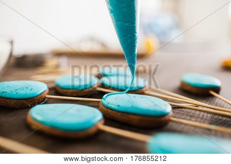 Preparing easter cookies with blue icing for decoration on rustic wooden table closeup